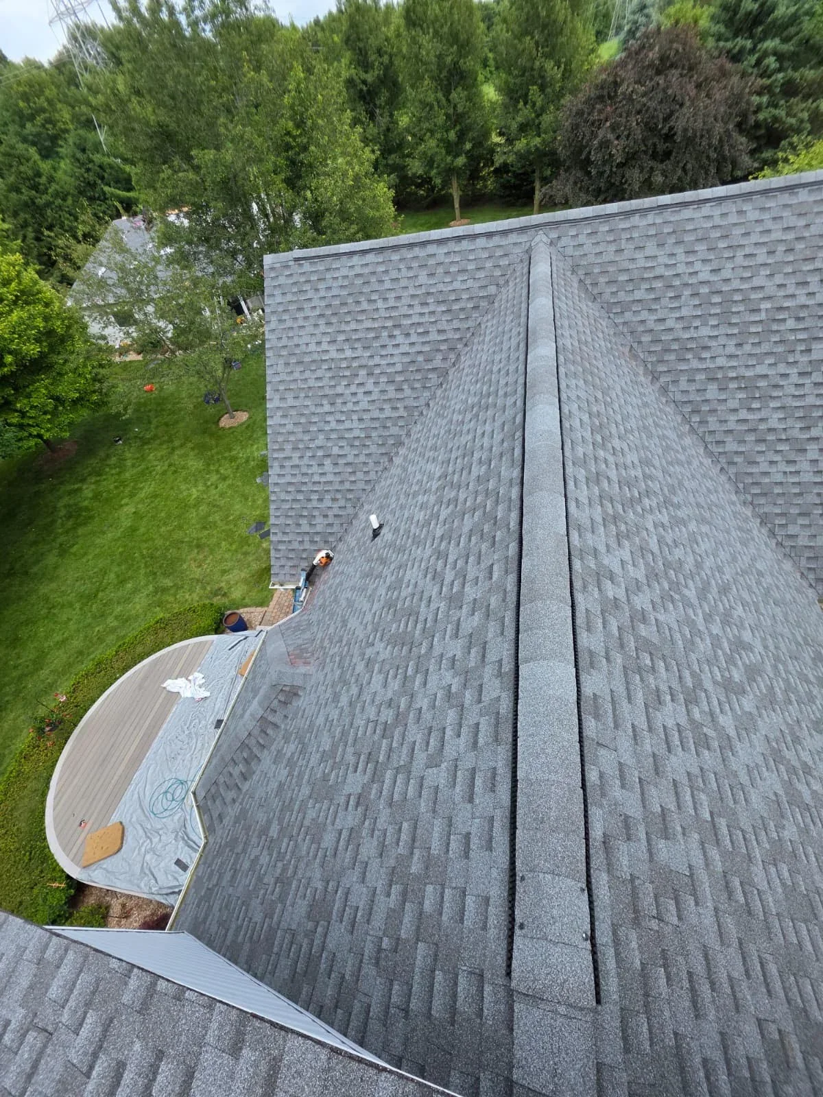 Gray architectural shingles installed on pitched residential roof with ridge cap and valley flashing